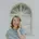 Woman standing in front of an arched window, laughing